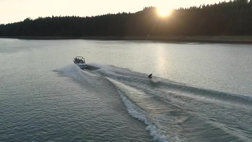 A man on a water ski dumps a wave created by the boat pulling him