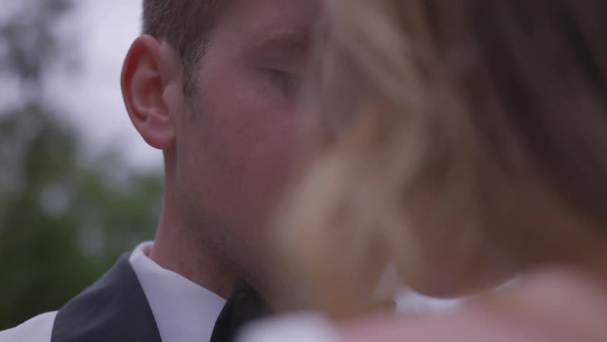 A woman kisses a man wearing formal attire