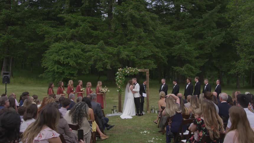 A bride and groom kiss at the outdoor wedding ceremony