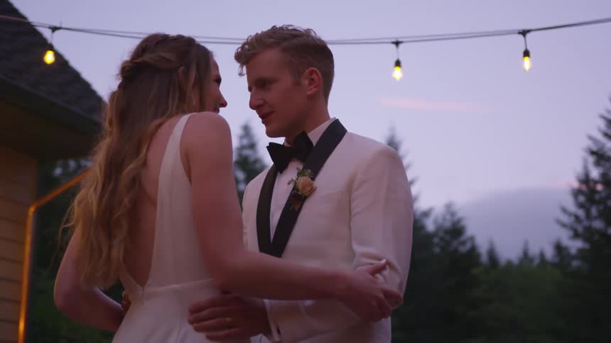 A bride and groom dance and kiss at their outdoor wedding reception