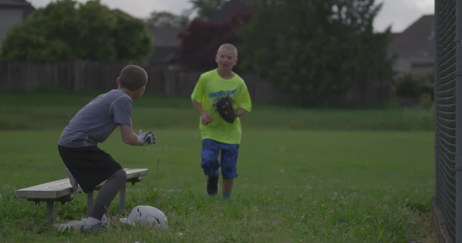 Boys meet in a field and run off holding baseball equipment