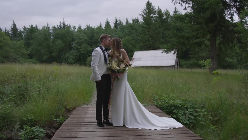 Bride and groom posing and kissing on deck in the middle of a forest