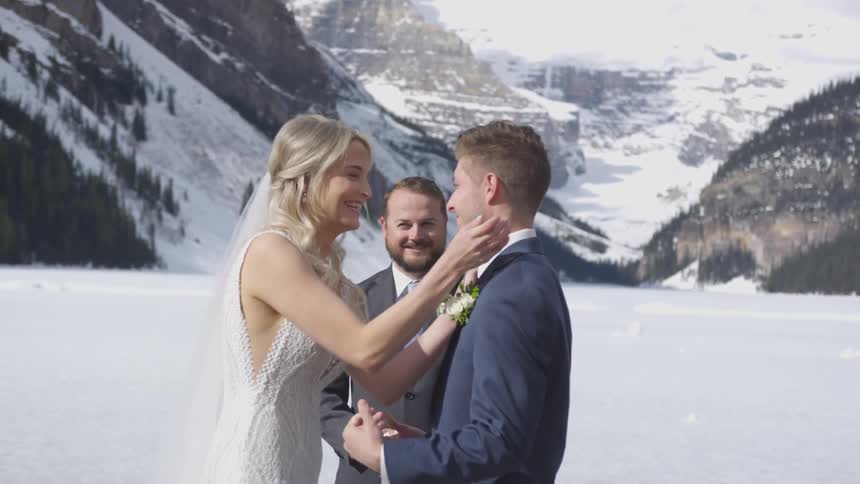 A bride and groom kiss at their wedding ceremony in snowy mountains