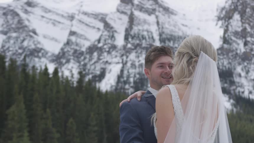 Bride and groom embrace with mountain and forest as backdrop