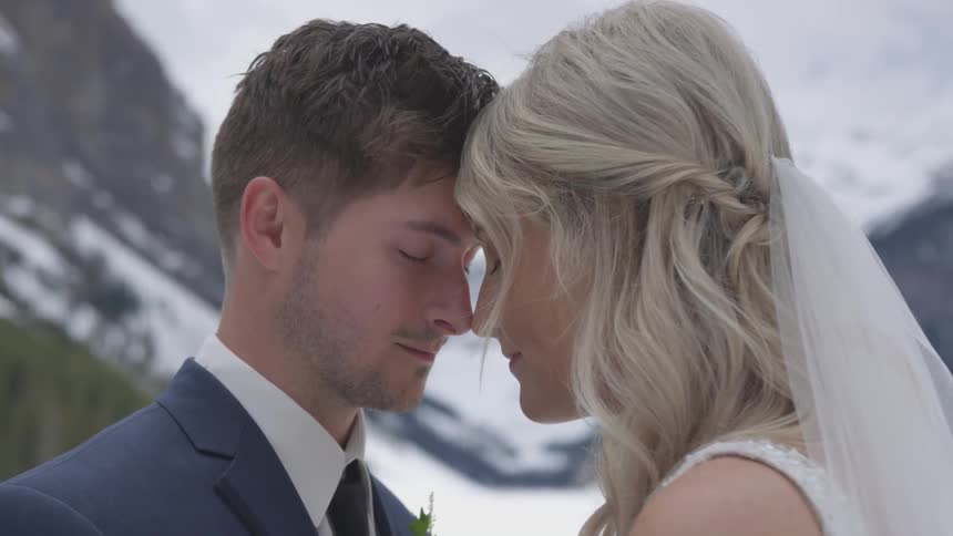 A bride and groom stand outside with their noses together