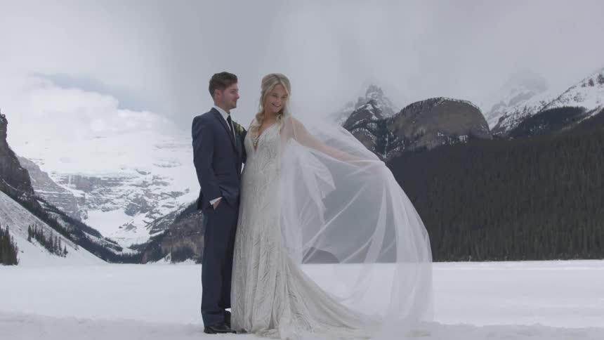 Bride and groom standing outdoors in the snow with mountains behind them