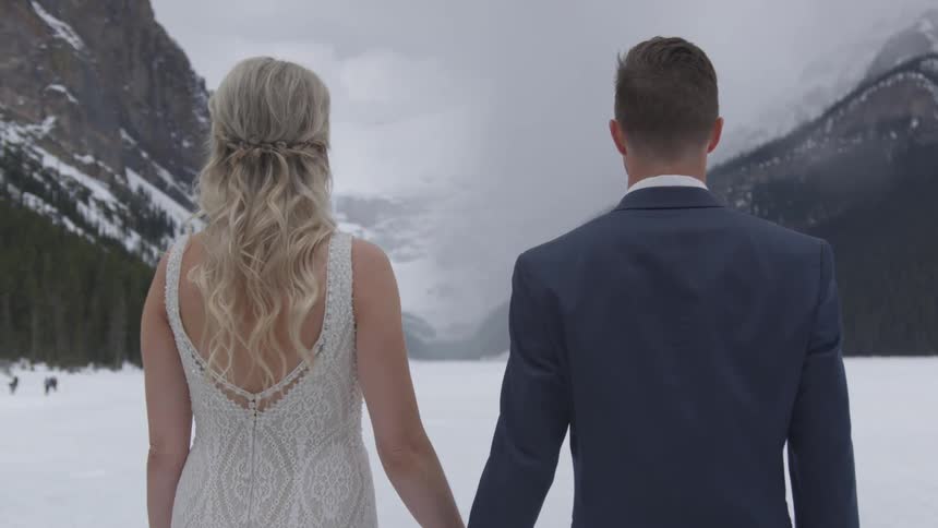 Bride and groom holding hand in the middle of a snowy field