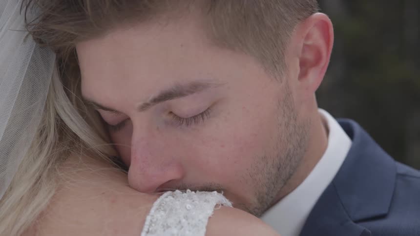Groom rests his cheek on the brides shoulder while keeping his eyes closed