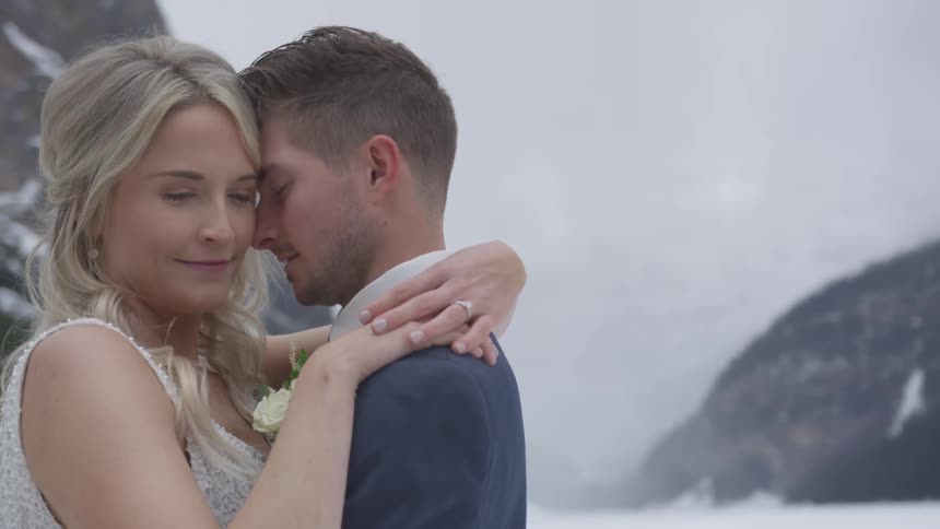 Bride and groom hold each other in the valley with the scene of snow covered mountains