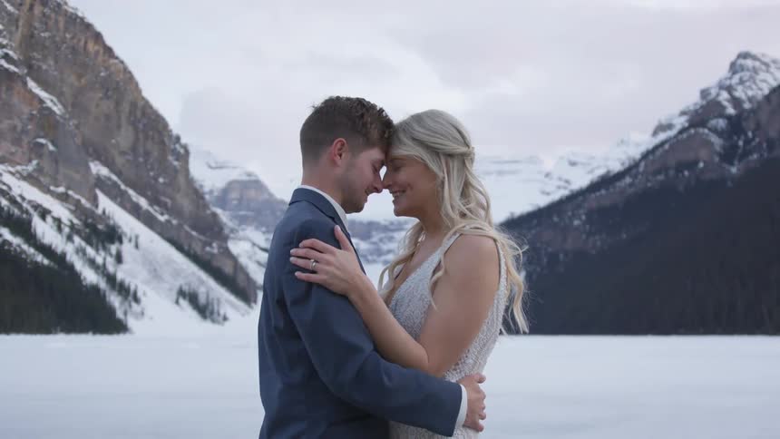 A man and woman hug while standing in the snow