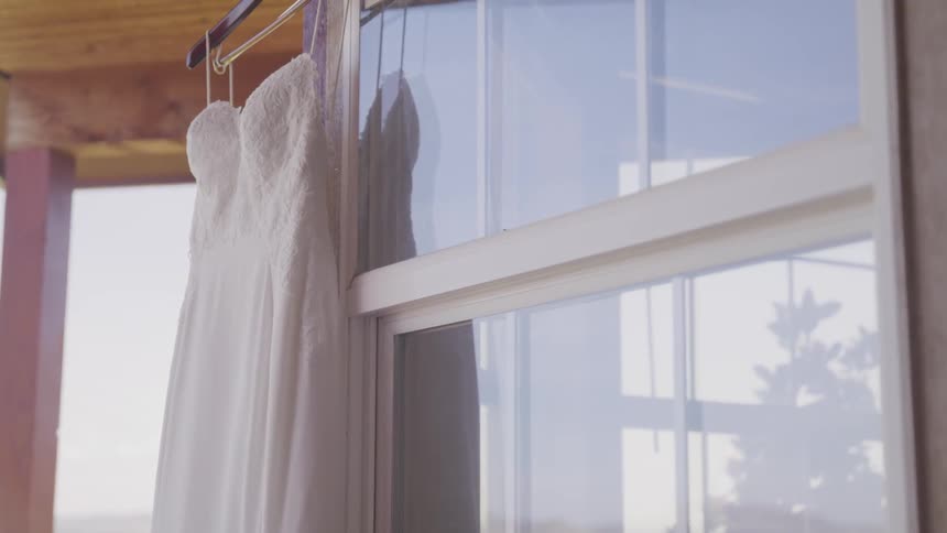 A wedding dress hangs on a hanger outside