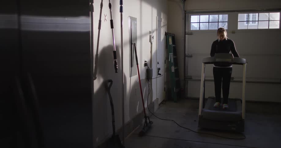 A woman walking on a treadmill in a garage