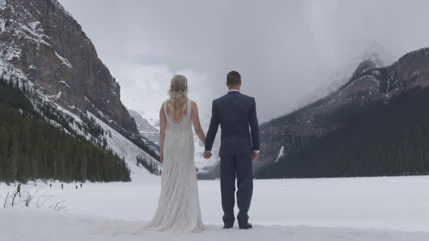 Bride and groom holding hands on the middle of a snowy mountain