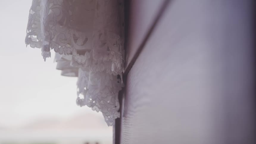 A curtain slightly blowing in the wind on the side of a house