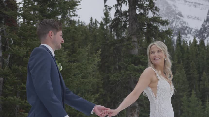 A bride and groom walk outside holding hands