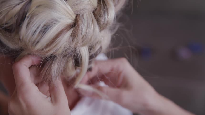 A woman is fixing another womans hair into a formal fashion