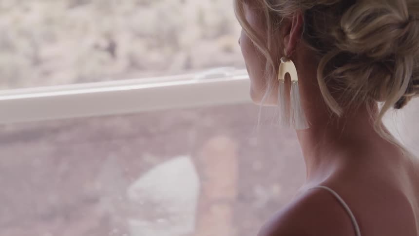 Woman in a white dress looking out a window