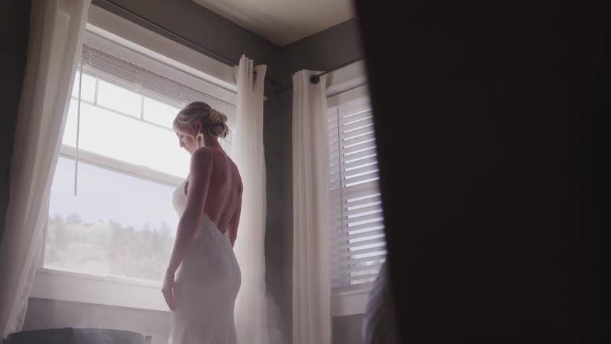 A woman bride looks outside from the window