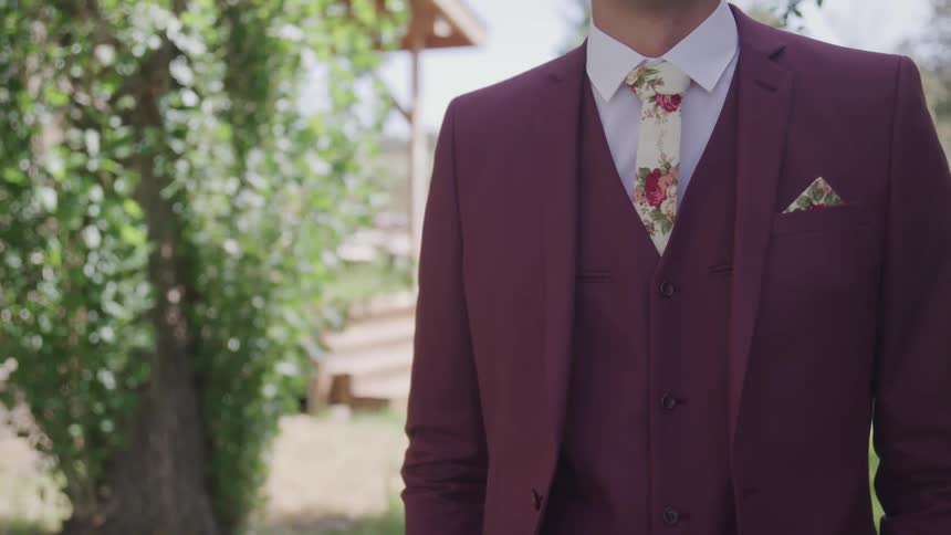 A groom stands in the yard beside a building