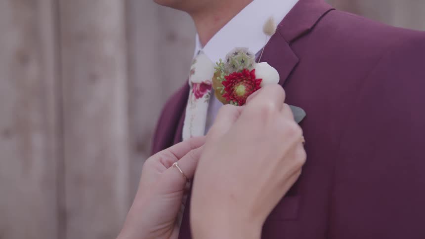 A woman fixes a boutonniere on a mans suit