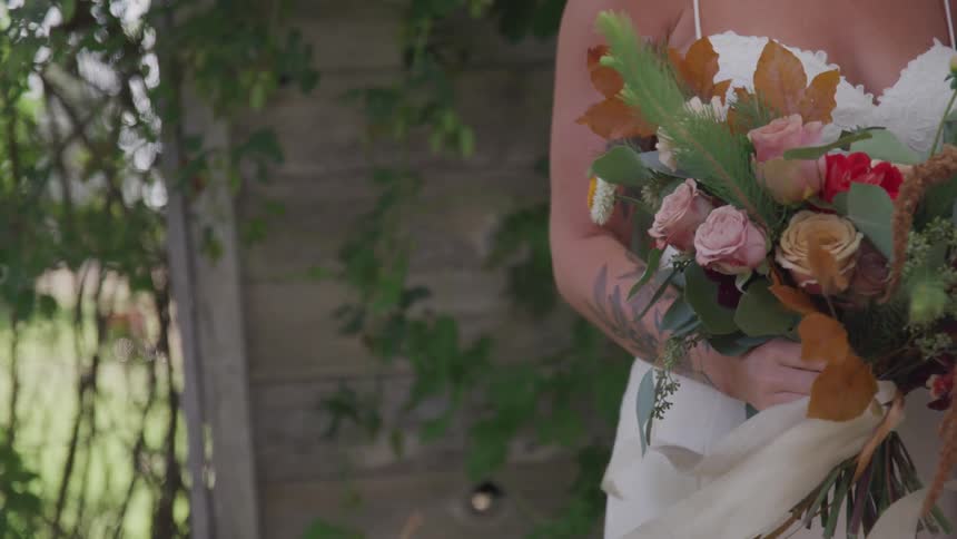 A bride holds a bouquet while the wind blows it