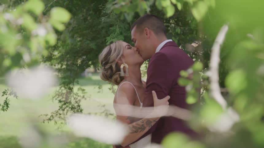 Bride and groom kiss under tree