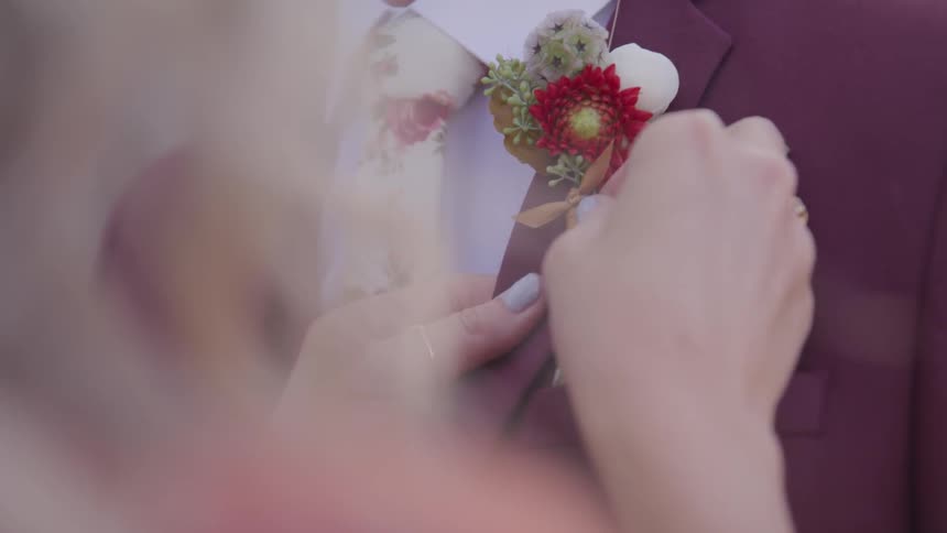Groom put a flower ornament on the suit