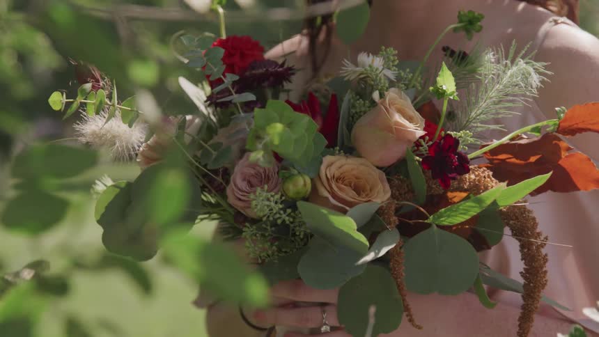 A woman stands outside holding a bouquet of flowers