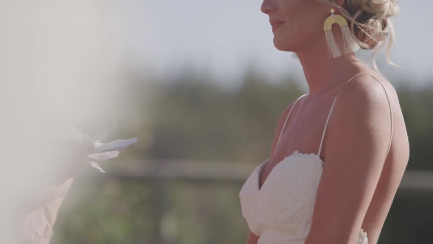Bride in a wedding dress stands still as the breeze blows her hair