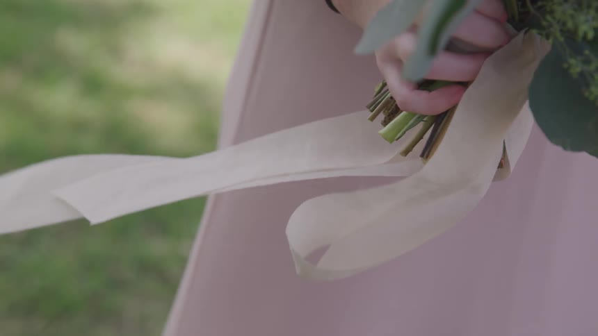 Woman dressed in lilac gown holds floral bouquet