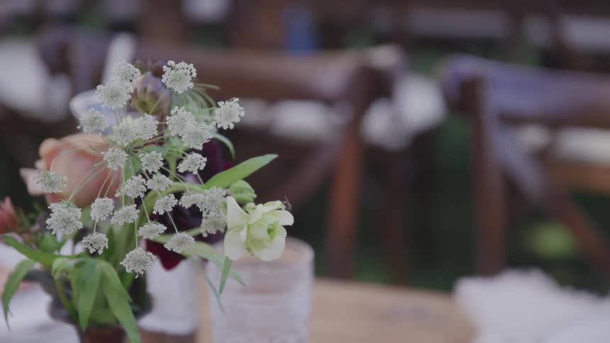 A small arrangement of flowers sitting on a table gently moving in the wind