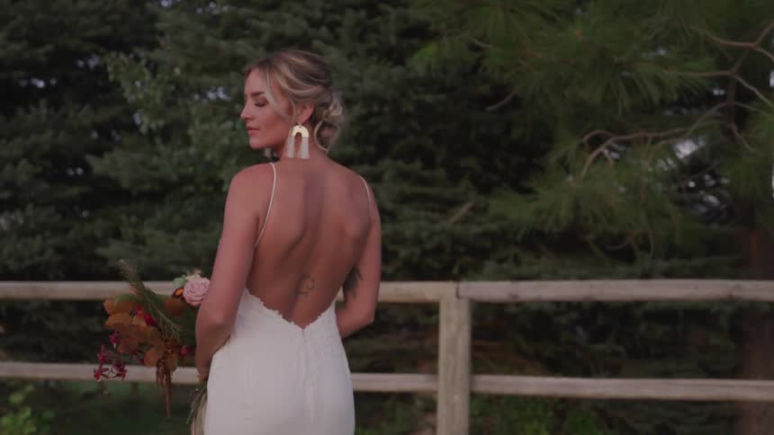 A woman stands wearing a dress