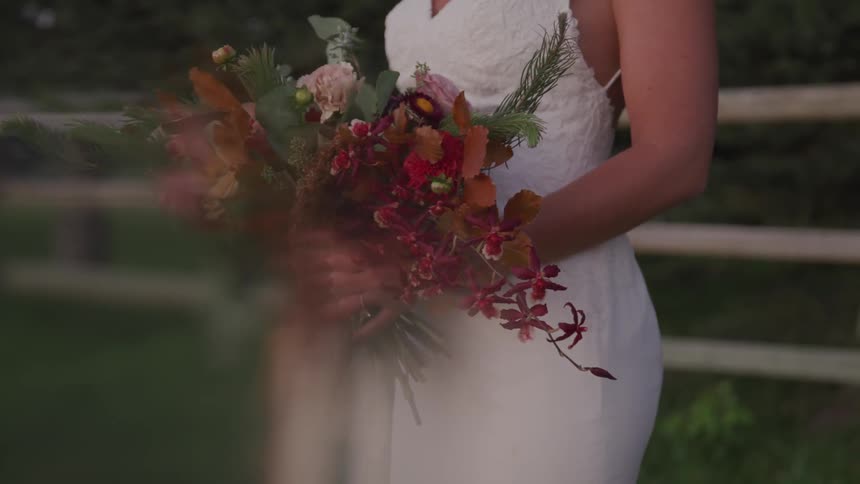 A woman in a wedding dress holds a bouquet of flowers