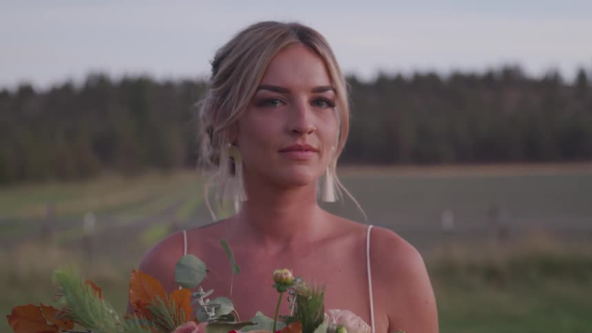A woman is standing in a field holding a bouquet of flowers