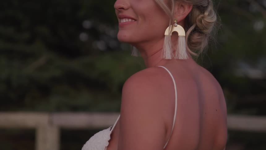 A woman wearing a dress is smiling outdoors
