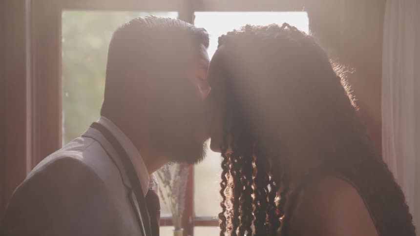 Couple kissing in front of window at day