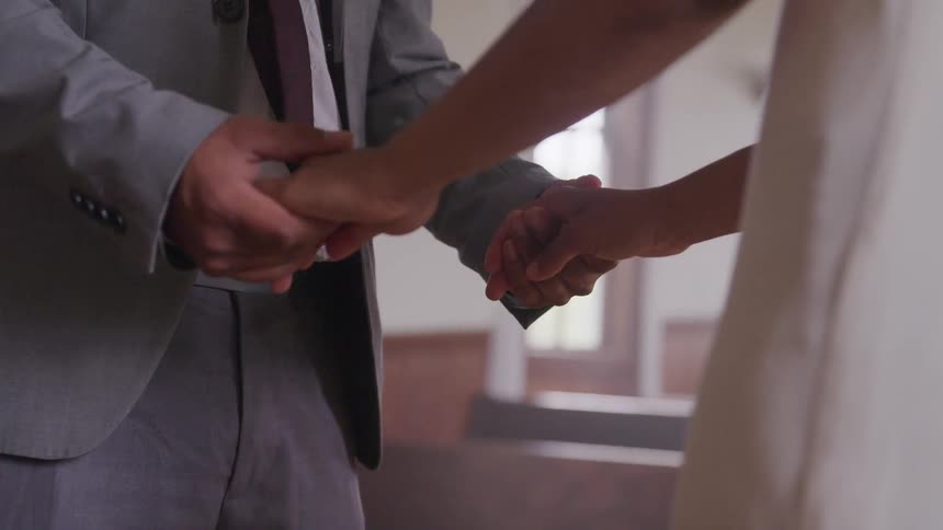 Groom and bride hold hands during the wedding ceremony
