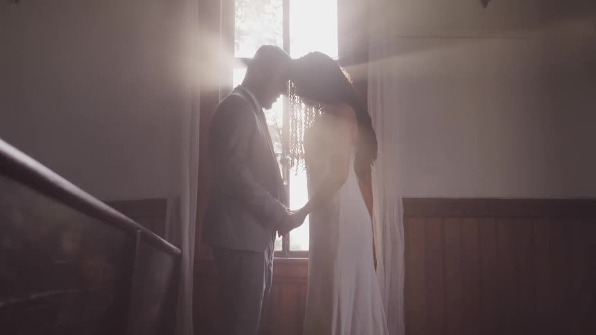 A bride and groom stand with their heads together