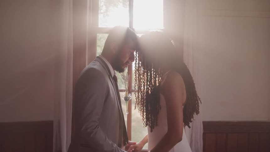 Groom and bride touching them forehead with a sun flare behind them