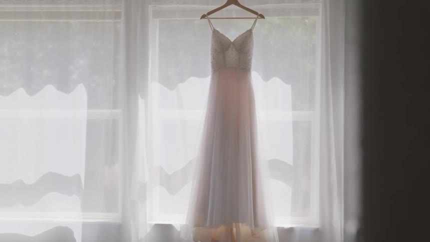 White wedding dress hanging by the window in a room