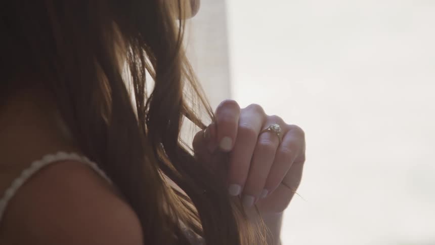 Woman wearing ring holds her hair during daylight
