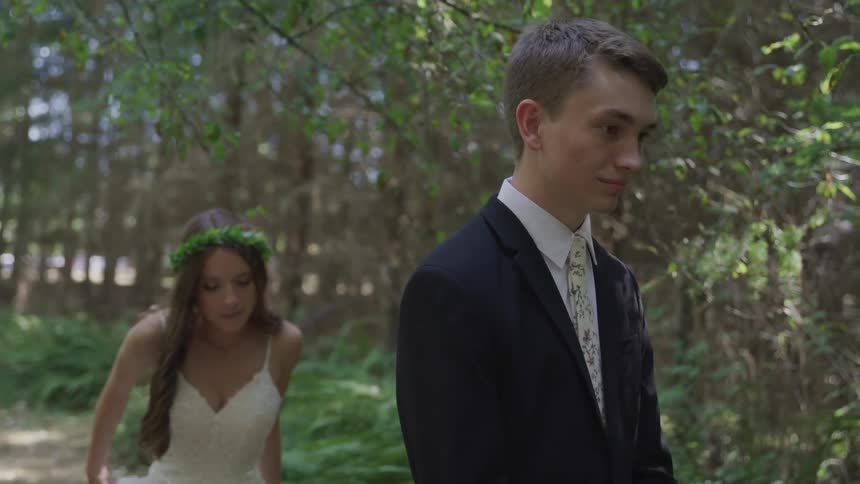 Bride goes up to groom who waits for her in the forest