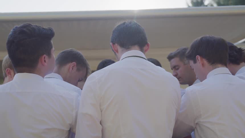 A group of man gather under the sun flare