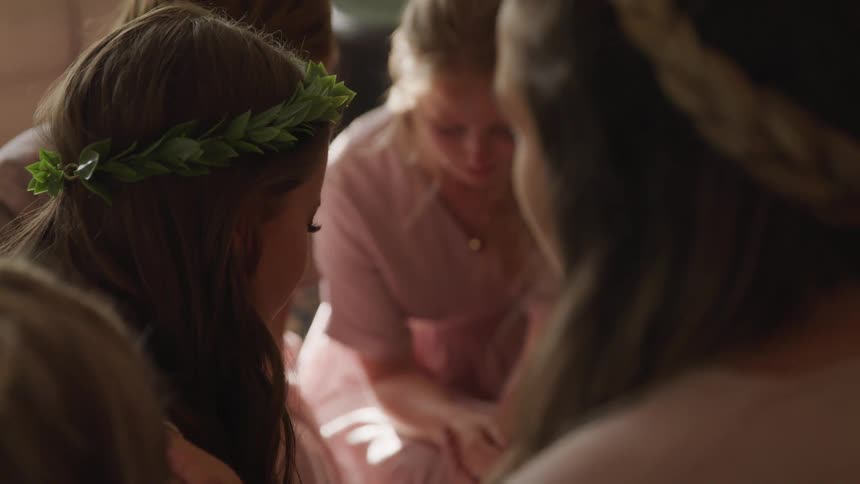 Girls sit in a circle with their hands folded and eyes closed while looking down
