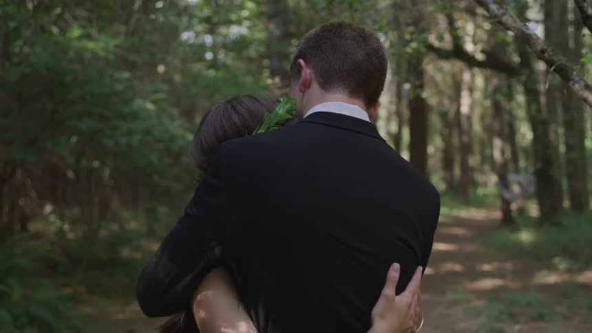 Groom and bride cuddle each other in the forest during daylight