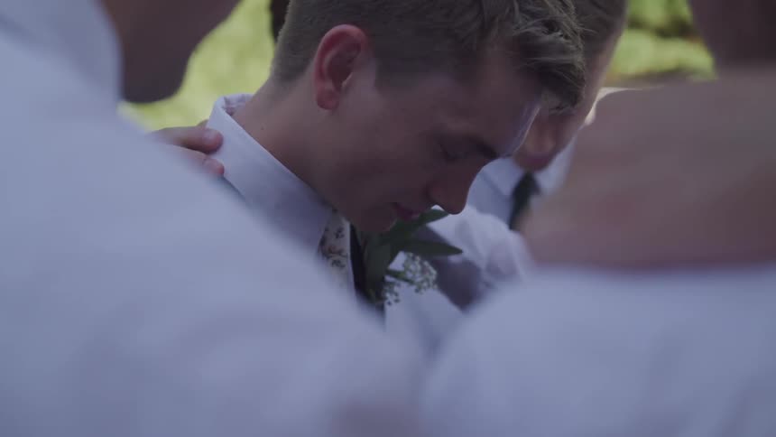 Men in shirts and ties laying hands on each other and praying