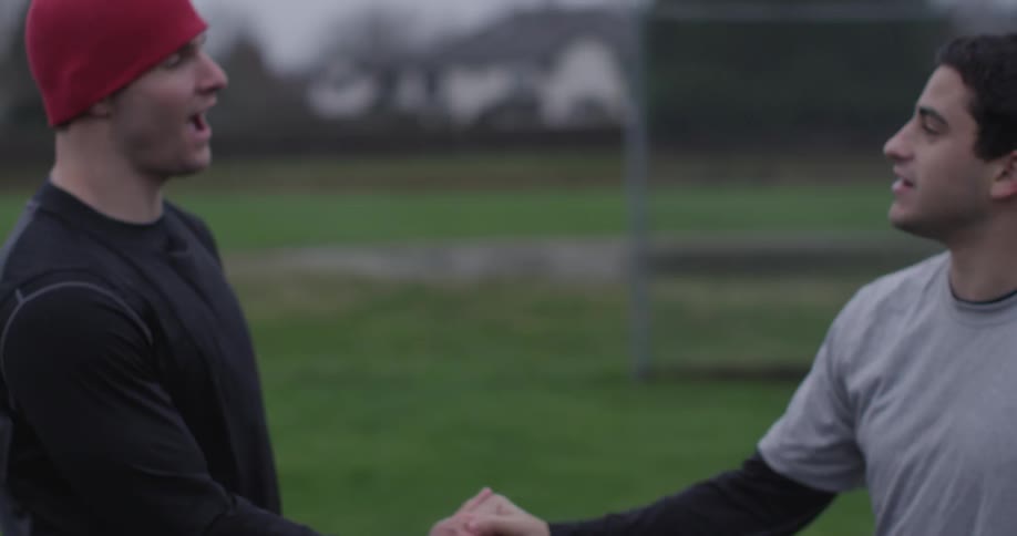 Two men hug on an outdoor field