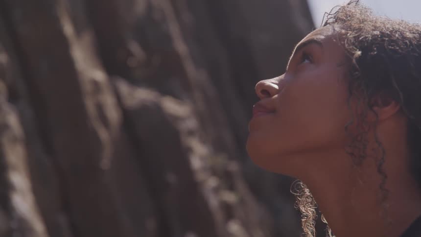 A woman stands looking at a rock formation in front of her