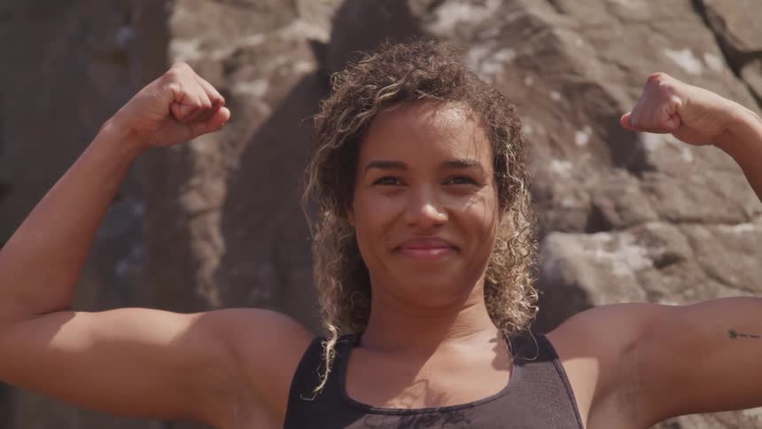 A woman raises her arms and flexes to share her muscular biceps