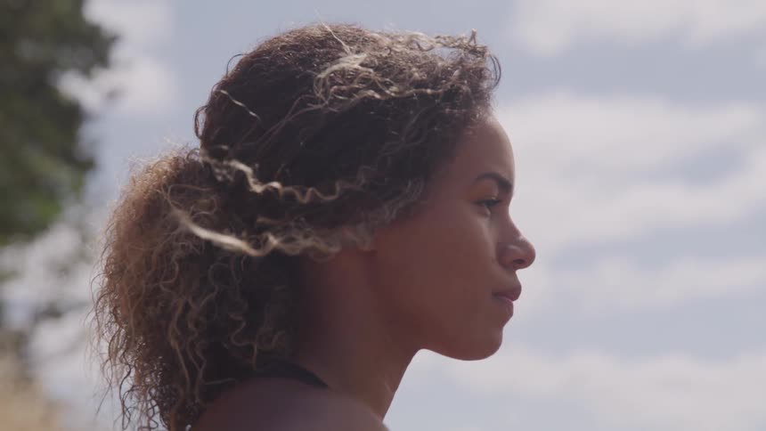 Black woman looks ahead outdoors during the day